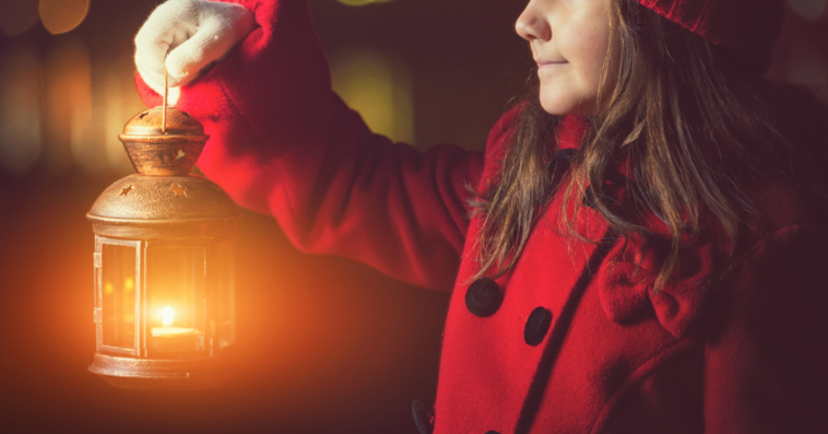 girl in red coat with lantern walking at night