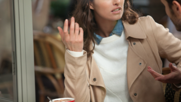 A woman emphatically gesturing while talking to another man.