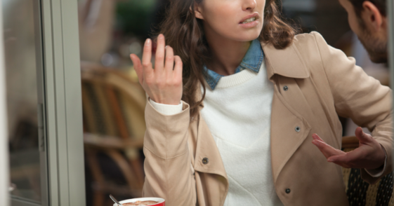 A woman emphatically gesturing while talking to another man.