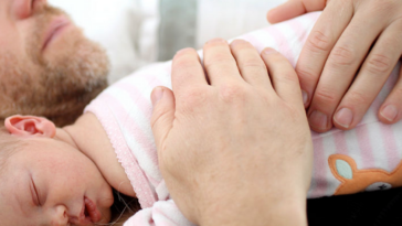 A baby lying asleep on a man's chest.