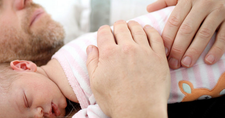 A baby lying asleep on a man's chest.