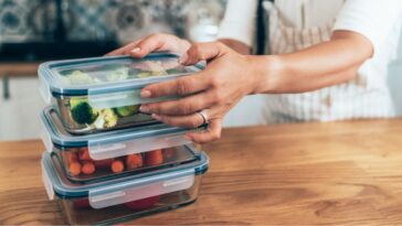 Close up of female hands holding glass containers with fresh raw vegetables.