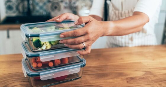 Close up of female hands holding glass containers with fresh raw vegetables.