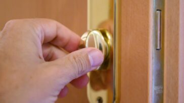 Close-up of a person's (male) hand opening or closing a door latch.