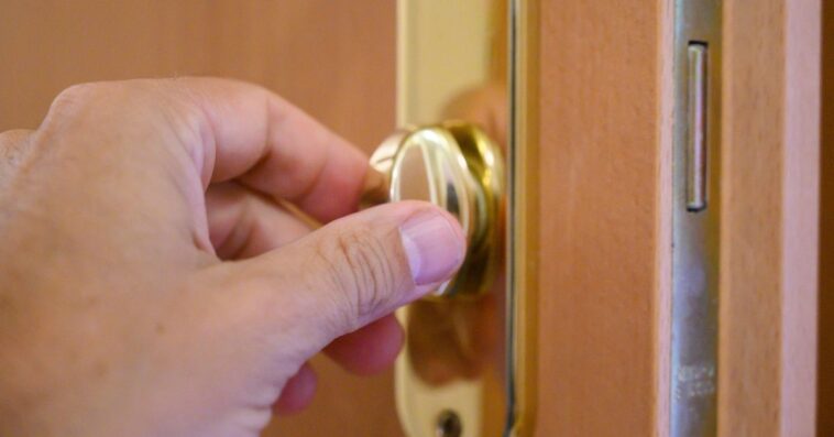 Close-up of a person's (male) hand opening or closing a door latch.