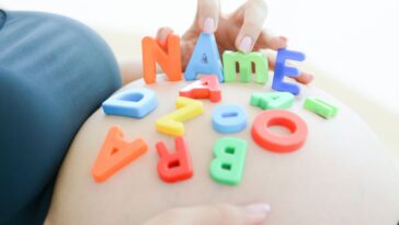 Expectant mother with letter blocks spells name on her pregnant belly.