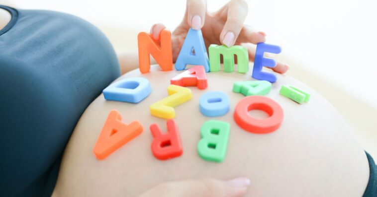 Expectant mother with letter blocks spells name on her pregnant belly.