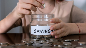 A teenage girl putting coins in a jar.