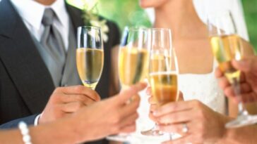 Bride, groom and wedding guests toasting with champagne, mid section.