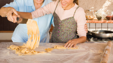 An older woman helping a younger woman cook.