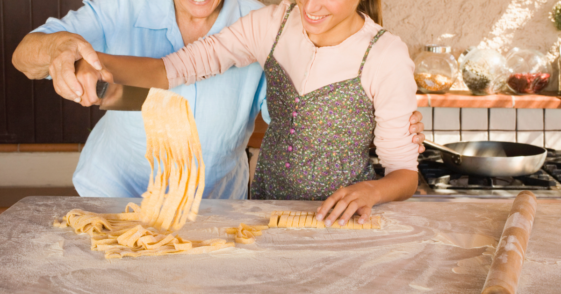 An older woman helping a younger woman cook.