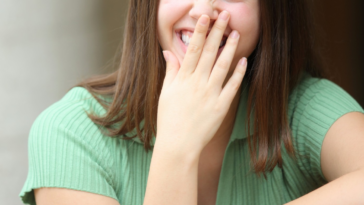 young woman covering her mouth as she laughs