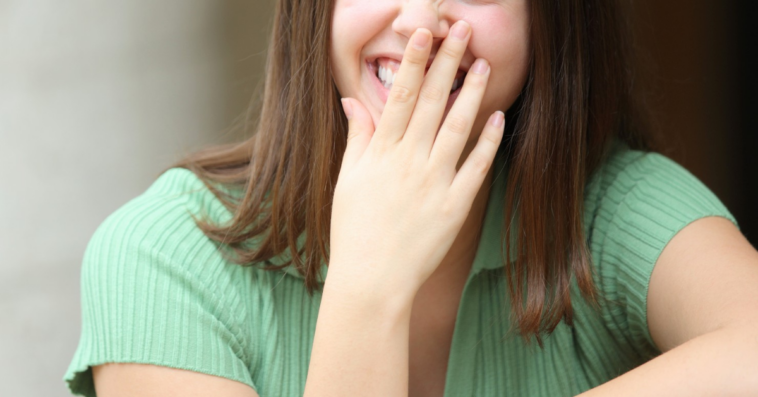 young woman covering her mouth as she laughs