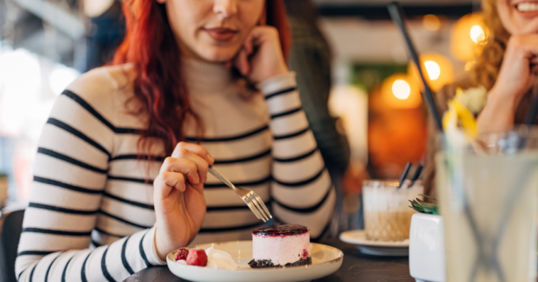 woman eating cheesecake in restaurant