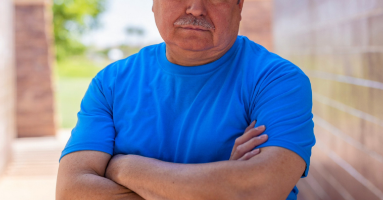 frowning older man with arms crossed