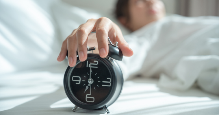 woman snoozing alarm clock