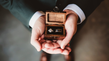 man holding box holding two wedding rings