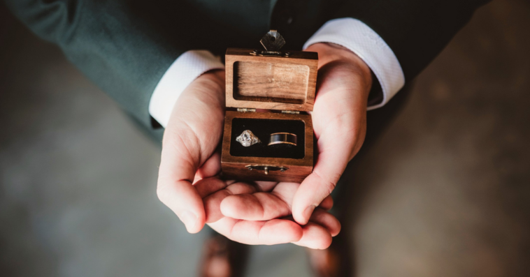 man holding box holding two wedding rings