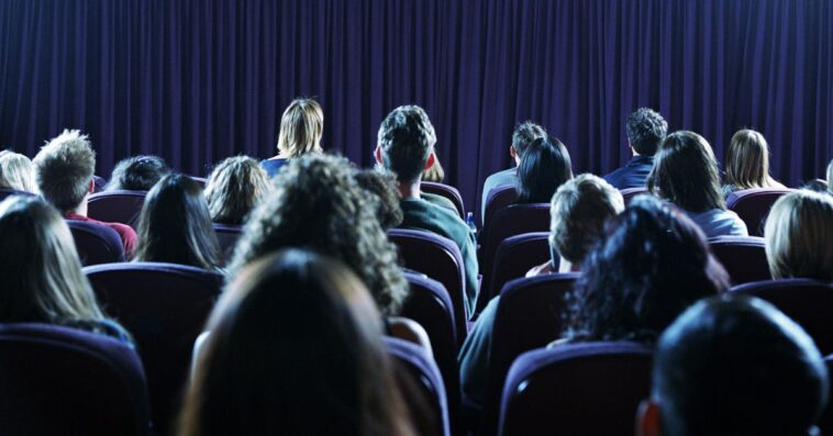 Rear view crowd of people in a movie theater.