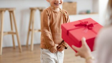 Cheerful mother receiving a present from her small son at home.