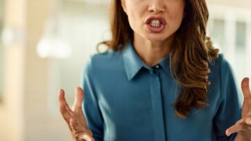 Angry female entrepreneur standing in a hallway and looking at camera.