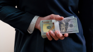 A man holding a pile of money behind his back.