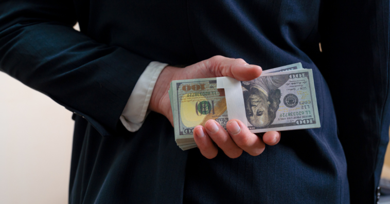 A man holding a pile of money behind his back.