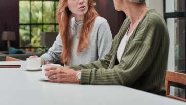 A younger woman having a conversation with an older woman at a counter.