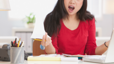 A woman sitting at her desk with an annoyed expression on her face.