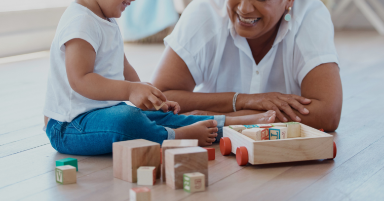 older woman on floor playing with toddler