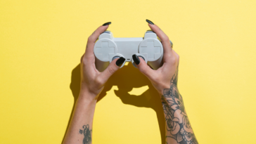 A woman with tattooed arms holding a game controller.