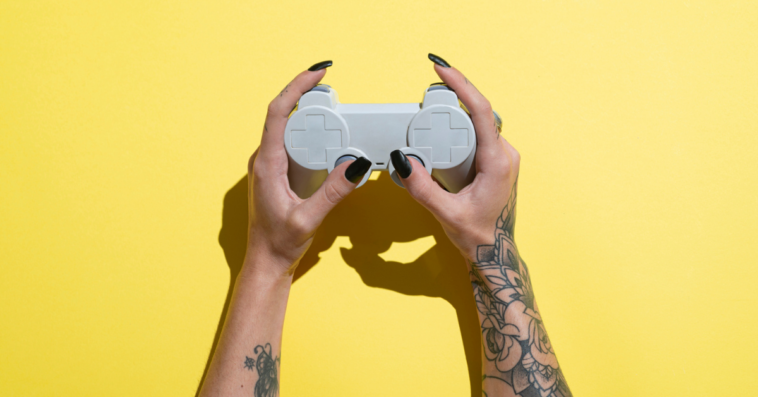 A woman with tattooed arms holding a game controller.