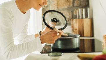 A woman stirring a pot on a stovetop.