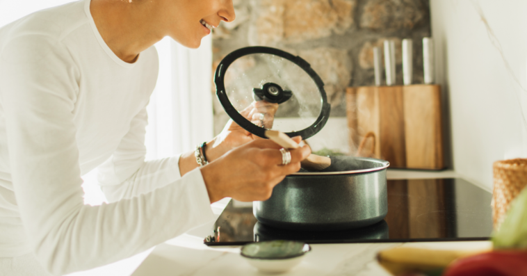 A woman stirring a pot on a stovetop.