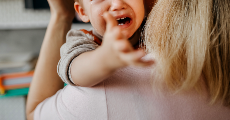 A woman holding a crying baby.