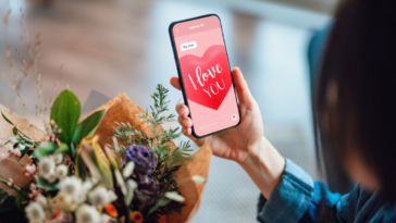person holding bouquet while looking at phone screen that says "I love you"