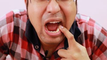 man poking at teeth after meal