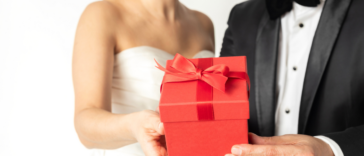 A Bride and groom holding a gift in red wrapping.