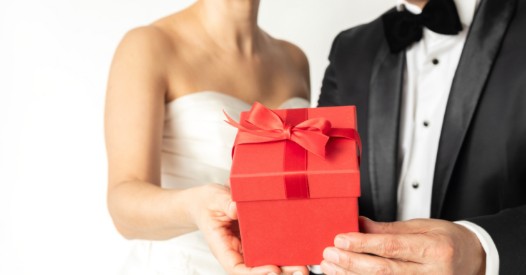 A Bride and groom holding a gift in red wrapping.