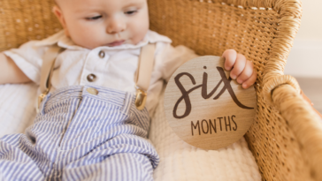 baby in bassinet with six months plaque