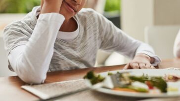 Shot of two confused looking children looking at vegetables on a plate that their parents expect them to eat while sitting around a table at home.
