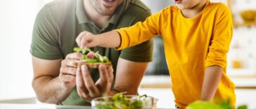 Happy father and son making a sandwich in the kitchen.