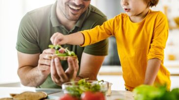 Happy father and son making a sandwich in the kitchen.