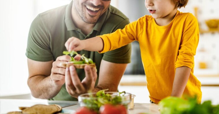 Happy father and son making a sandwich in the kitchen.