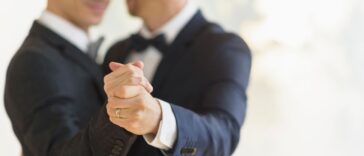 Gay grooms dancing and smiling at a wedding.