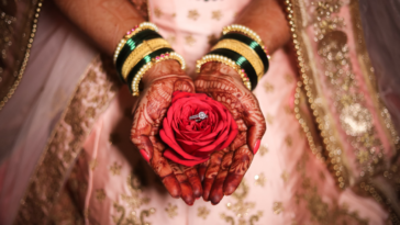 A Hindu bride holding a flower in her hands.