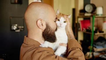 man holding cat against his face