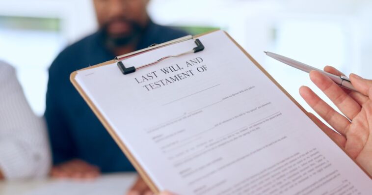 Close-up of a last will and testament about to be signed. A mature couple is blurred in the background.