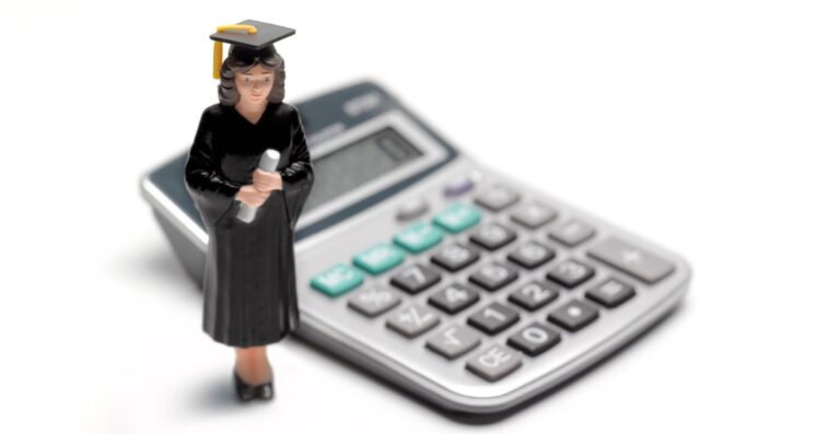 Toy figure of college graduate placed next to a calculator