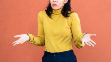 Woman in yellow turtleneck shrugging